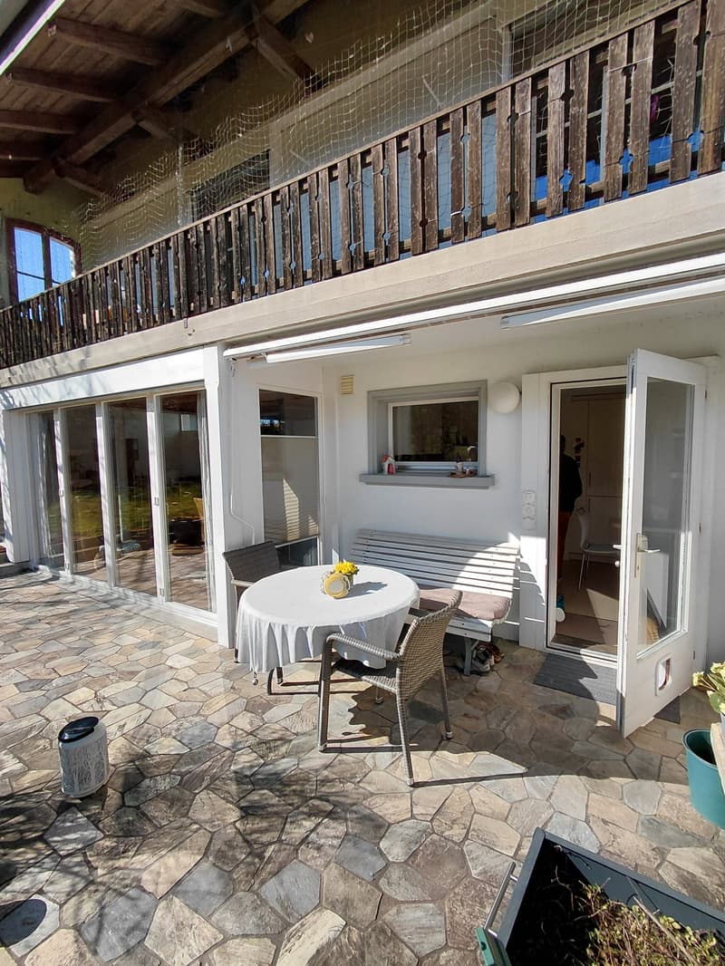 Courtyard with a patio table, chairs, bench, potted plants, an outdoor washing machine, an open door, and a balcony with railings