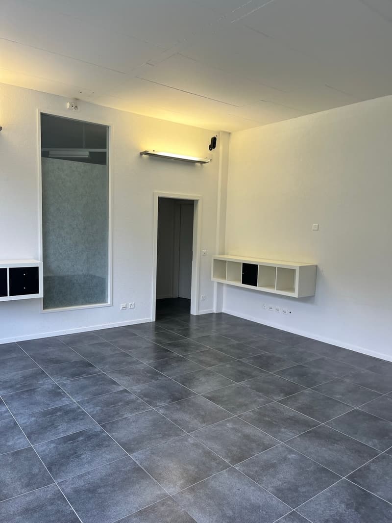 empty room with tiled floor, white walls, built-in storage, open door, lights