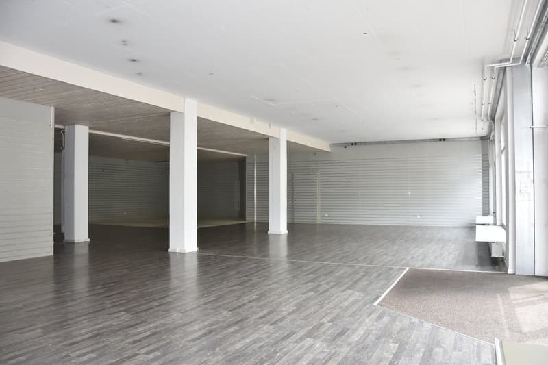 empty room, wooden floor, white walls, roll-up doors, white ceiling, central columns