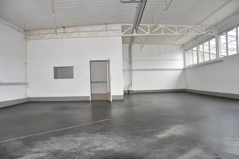 Empty room with white walls, gray floor, open door, windows, metal beams on ceiling