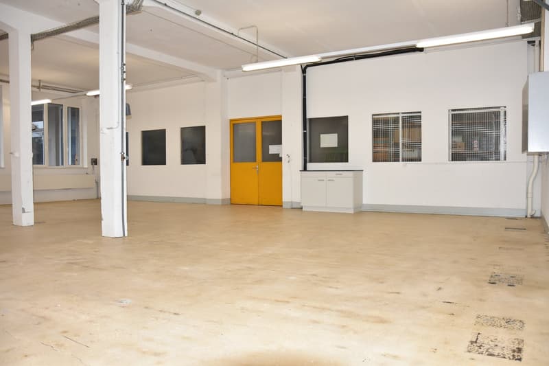 spacious room, high ceiling, white walls, white floors, industrial design, large yellow door, cabinets, windows, ventilation pipes