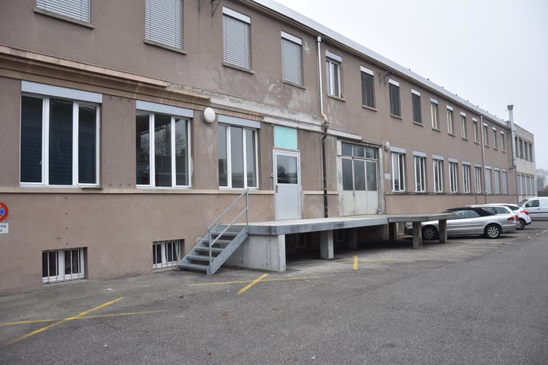 Industrial building, multiple windows, metal stairs, parking in front