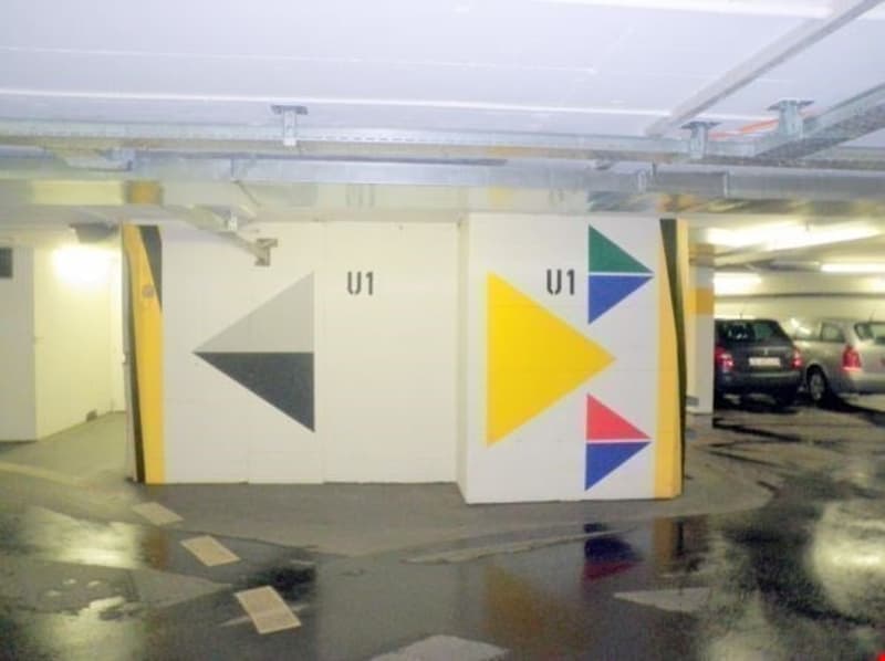Underground parking space with geometric wall art, yellow and gray color scheme, concrete floor