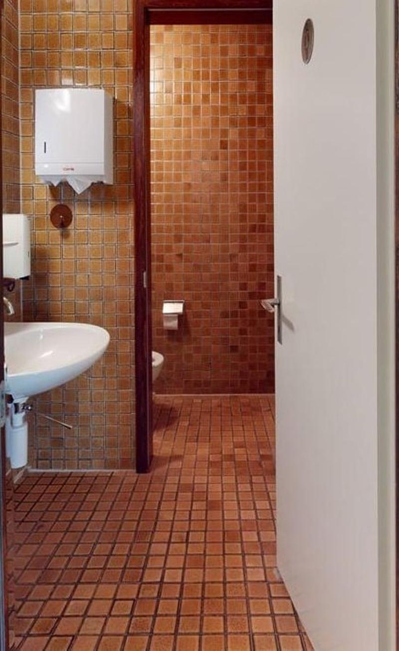 bathroom, brown tiles, white sink, white toilet, paper dispenser on wall