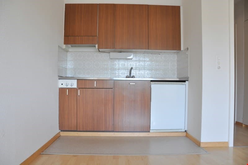 small kitchen with wooden cabinets, white appliances, tiled backsplash, wooden floor
