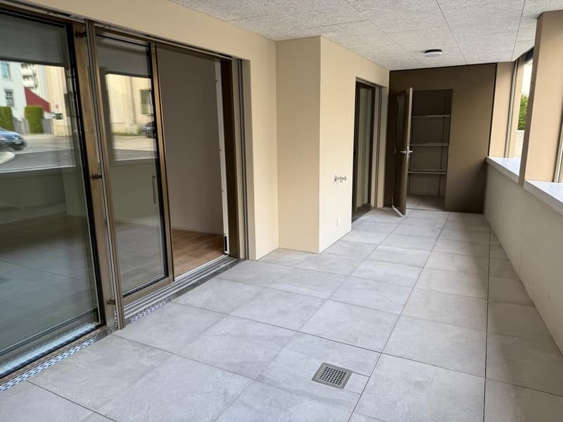 empty balcony, floor made of tiles, glass doors, windows, small drainage hole