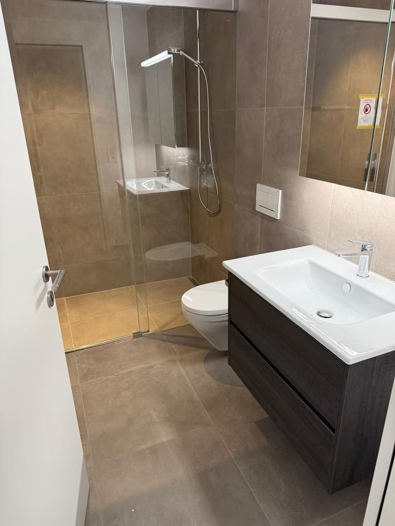 Bathroom with a toilet, shower, sink, tiled floor and glass door.