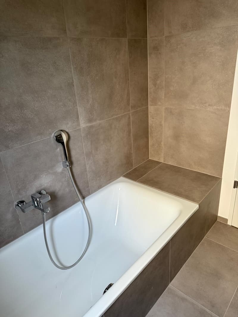 Bathroom with shower, bathtub, tiled walls, and tiled floor.