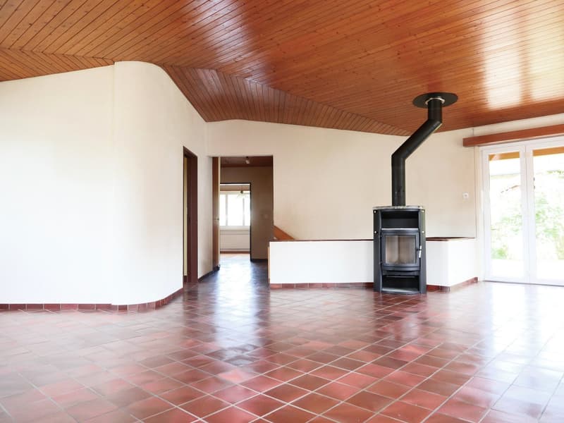 Empty room with red tiles, wooden ceiling, fireplace, glass doors