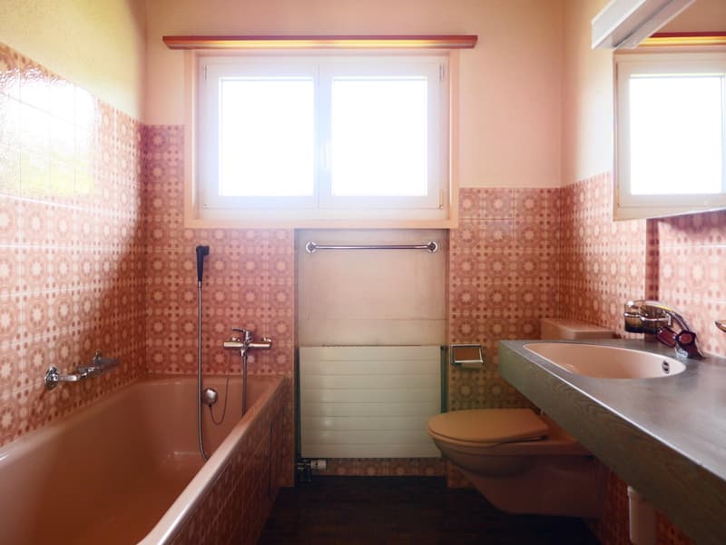 Bathroom with patterned tile walls, bathtub, toilet, sink, and a private washing machine