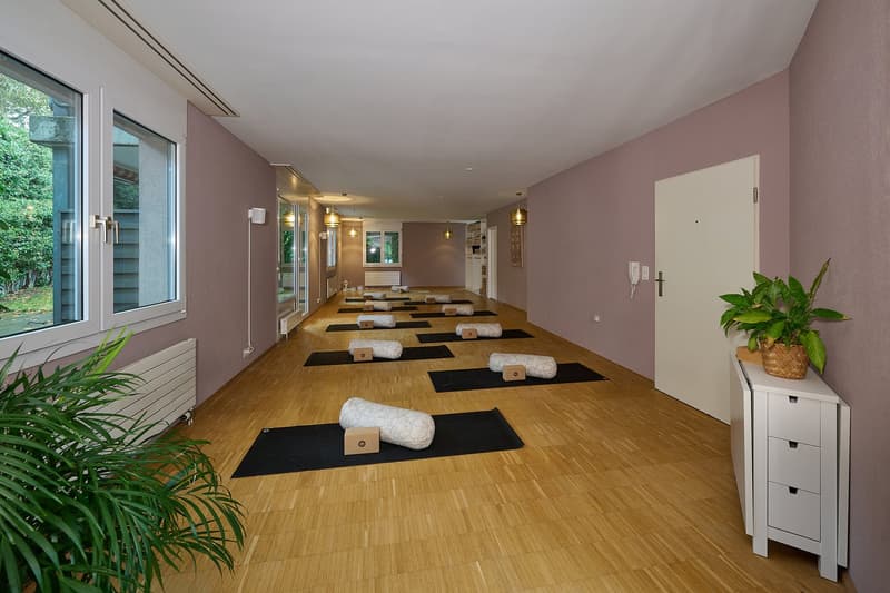 Yoga room, wooden floor, purple walls, windows, white yoga mats, pillows, plants, radiators, doorway