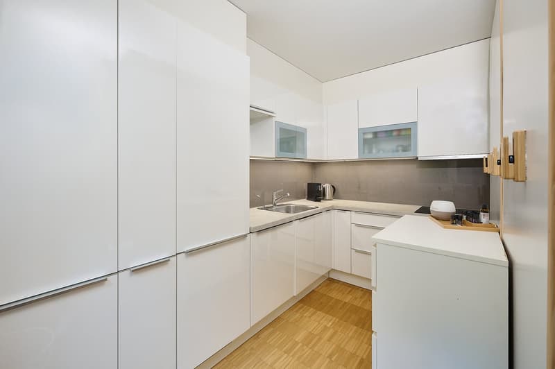 modern white kitchen with oak flooring and granite countertops