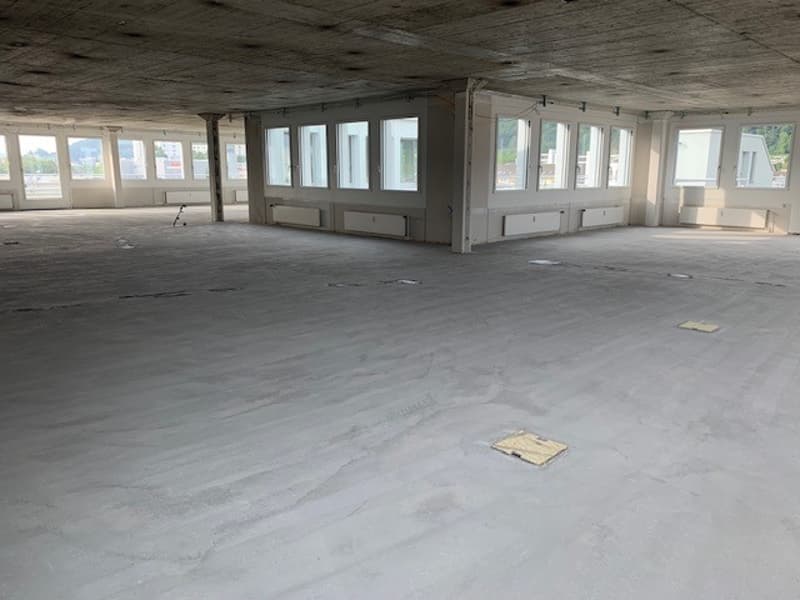 empty room, concrete floor, exposed beams, large windows, unfinished