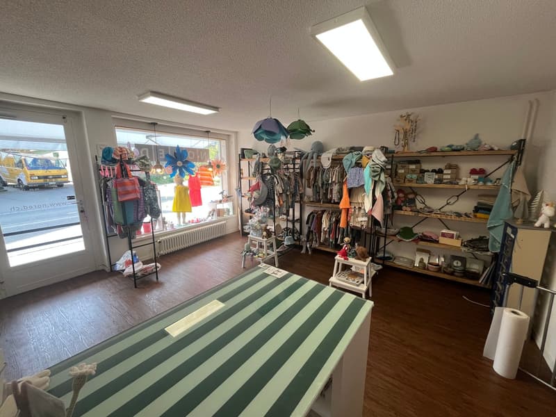 A room with wooden floor, shelves with clothes, a table with a green and white striped cover, a radiator, and a glass door.