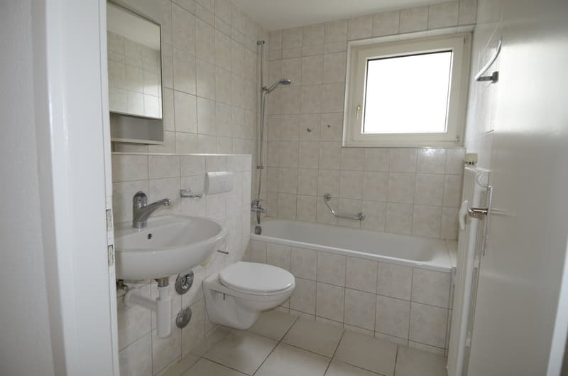 Bathroom with white tiles, white sink, white toilet, bathtub, shower head, mirror, window