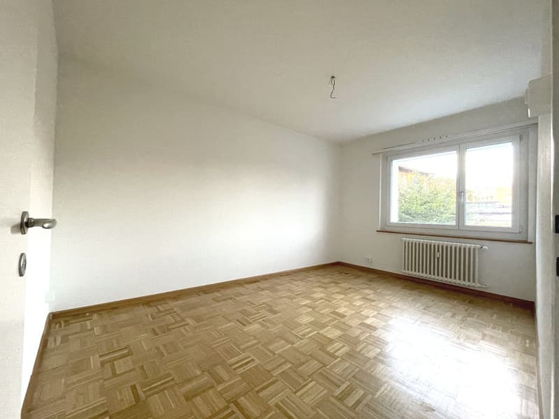 empty room, parquet floor, white walls, single large window, white radiator