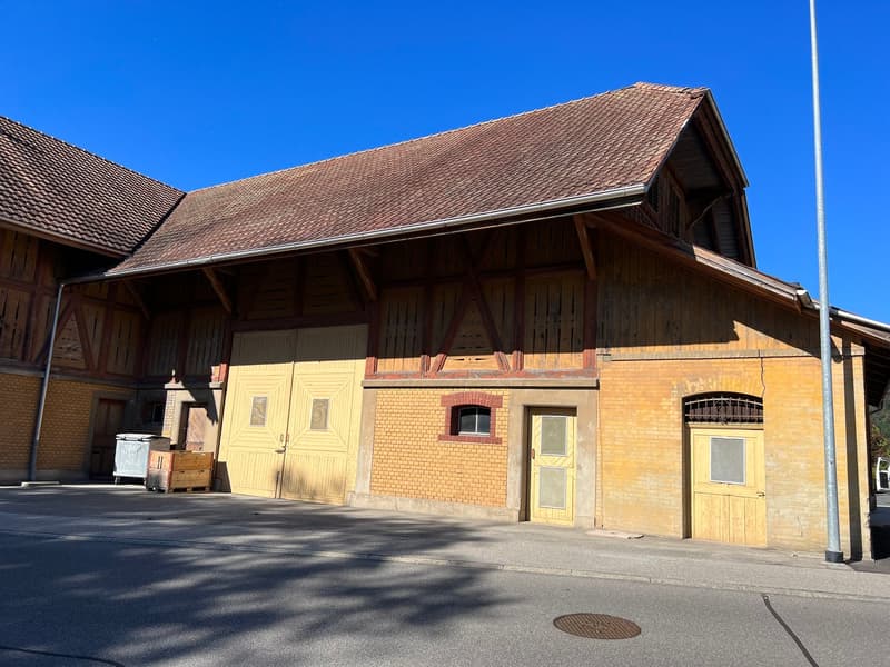 2 story building, wooden exterior, brown roof, yellow walls, double garage doors, parking space