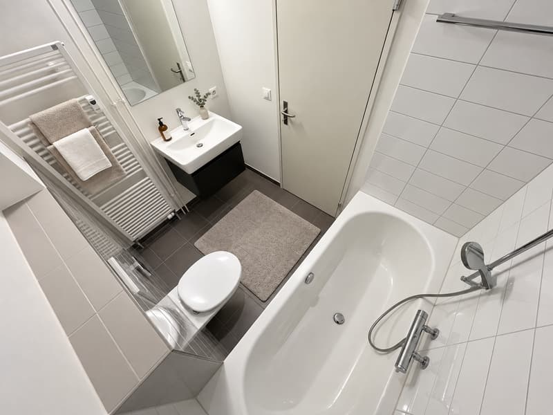 Badezimmer (Die abgebildeten Möbel wurden mithilfe von KI ergänzt und dienen ausschliesslich der Veranschaulichung der Räume; die Wohnung wird unmöbliert vermietet)