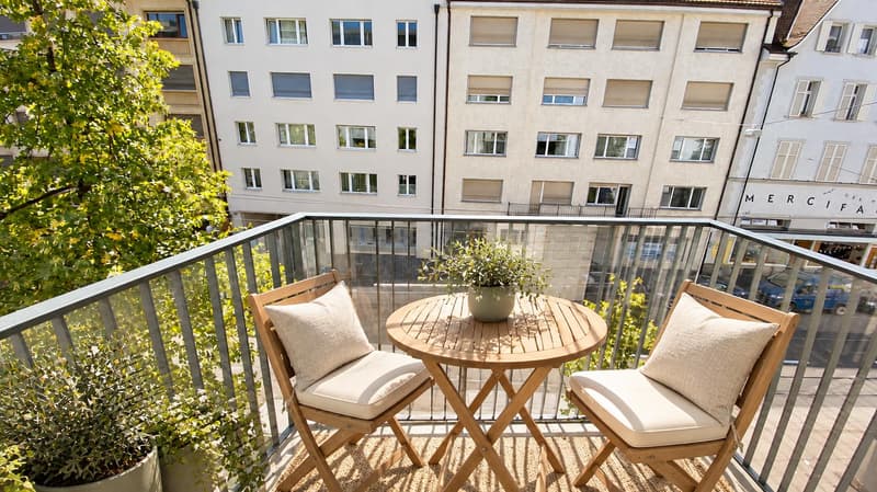 Balkon Strassenseite (Beispielfoto aus baugleicher Wohnung auf dem 2.OG; Abweichungen sind möglich) (Die abgebildeten Möbel wurden mithilfe von KI ergänzt und dienen ausschliesslich der Veranschauli