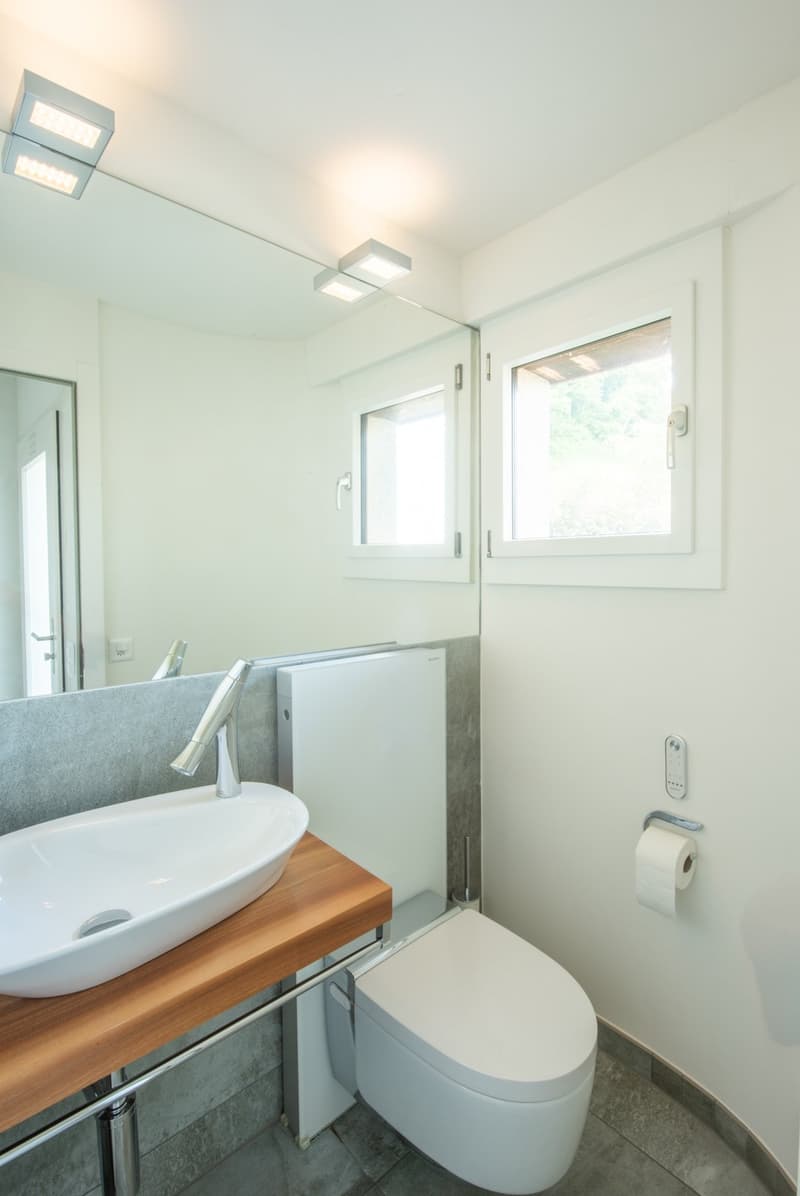 white modern bathroom with a sink, toilet, shower, and a window