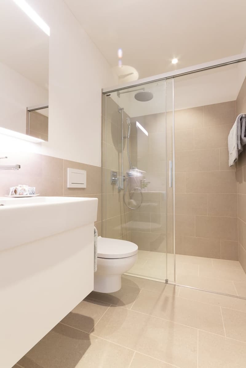 tiled floor, glass shower enclosure, white vanity, white toilet, towel rack