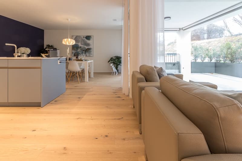 modern living room with open kitchen, hardwood floors, large windows, balcony with view