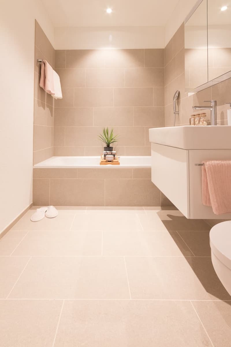 white bathtub, white sink, mirror, potted plant on sink, pink towels