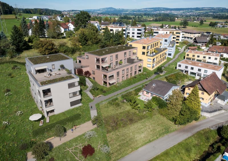 Aerial view of a residential area with multiple buildings, green roofs, balconies, and pathways.