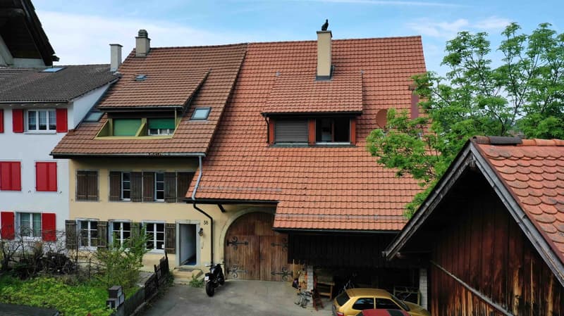 Two story house, brown tile roof, red shutters, yellow exterior, garage, street view, trees in the background