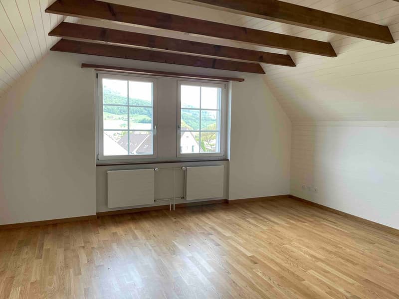 empty room, wooden floor, wooden beams on ceiling, two windows with view of landscape
