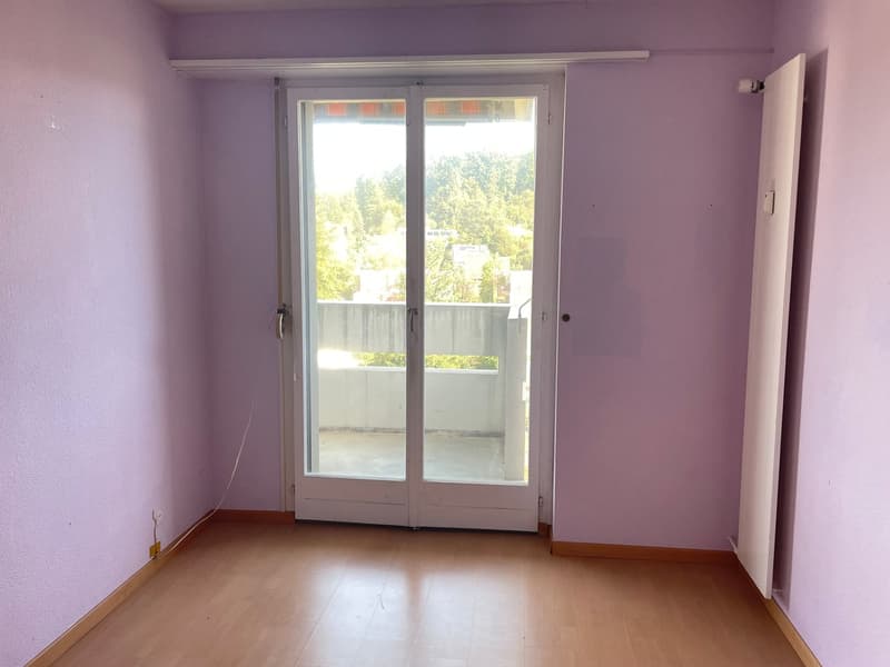 Empty room, wooden floor, sliding glass door to balcony, purple walls, two electrical outlets