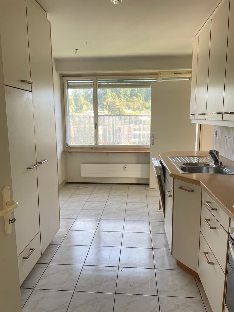 Kitchen has tile flooring, white cabinets, stainless steel sink, countertop, view to outside
