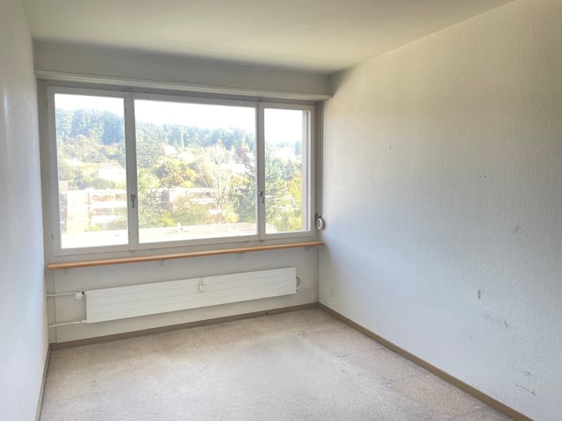empty room with large window and wooden sill, white walls, white radiator
