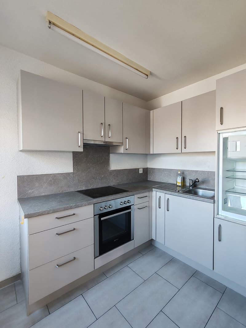 A modern kitchen with white cabinetry, a granite countertop, built-in gas stove, an extractor hood, and a stainless steel sink with a faucet.