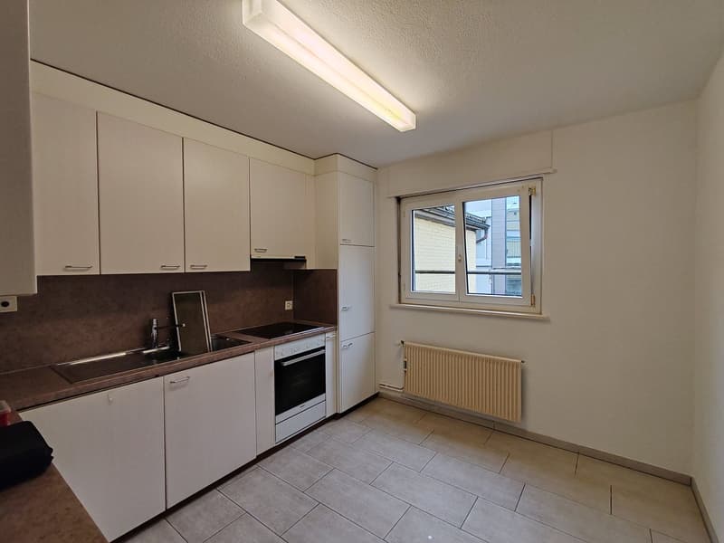 modern kitchen with tiled floor, white cabinets, integrated appliances, window