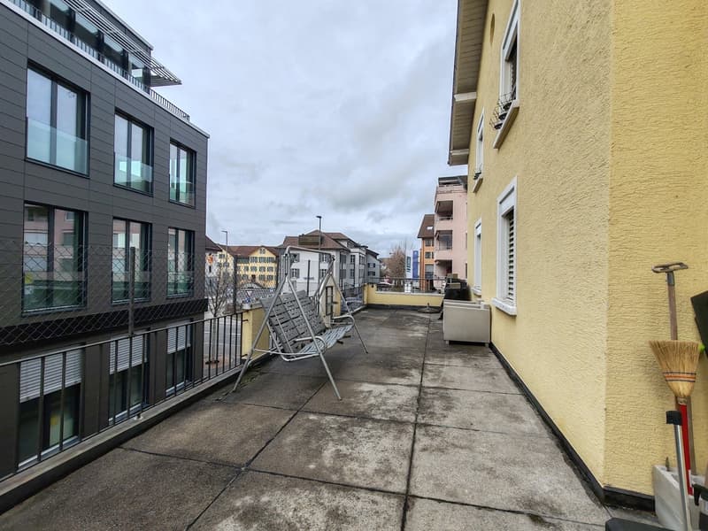 exterior of a building with a balcony, a swing, a broom, and a shovel visible