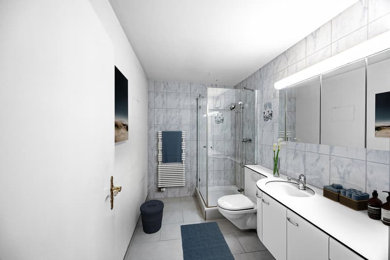 modern bathroom with white tiles, glass shower, white sink, white cabinets, blue rug, white toilet, towel rack