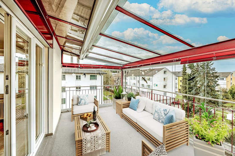 Balcony with glass roof, wooden furniture, plants, table with food, view of the city