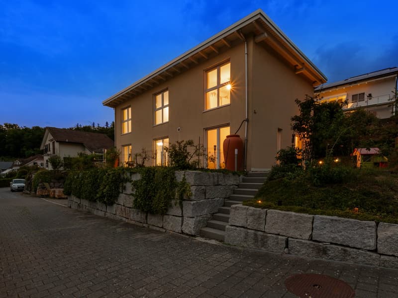 Two story house, beige walls, glass windows, concrete walkway, garden with stairs