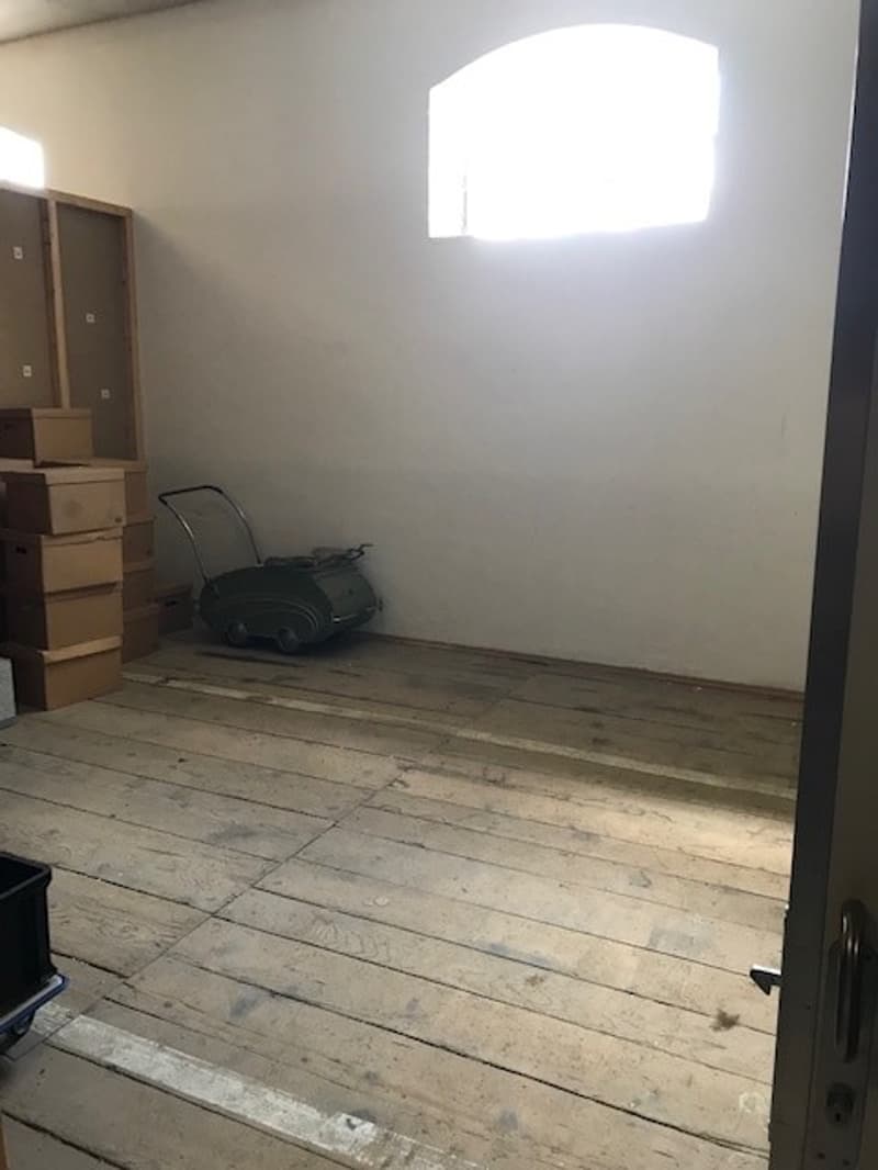 Empty room with wooden floor, boxes, and a window providing natural light.