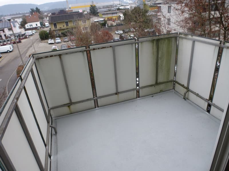 Apartment with a balcony overlooking a busy street and parking lot