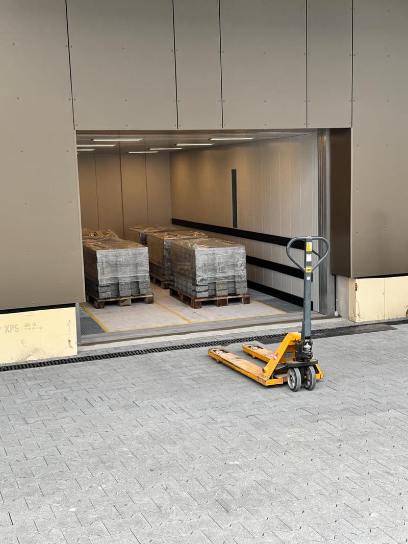 Industrial building with a large open door, palletized goods inside, forklift parked outside
