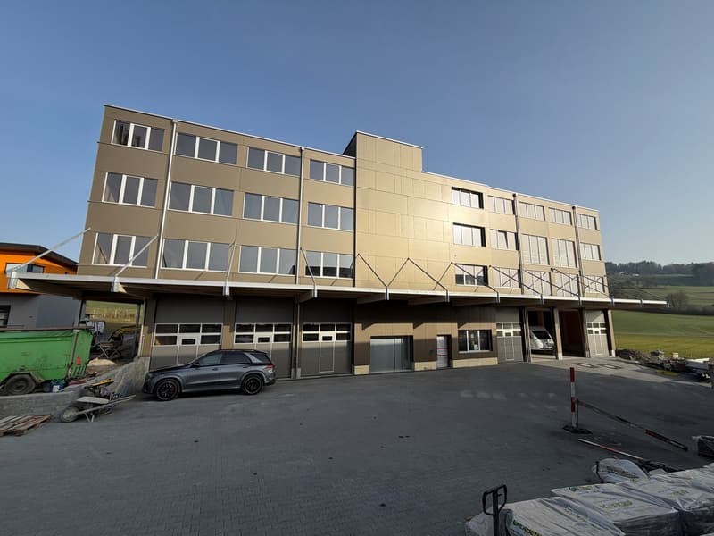 4 story building, brown exterior, multiple windows, garage, car parked in front