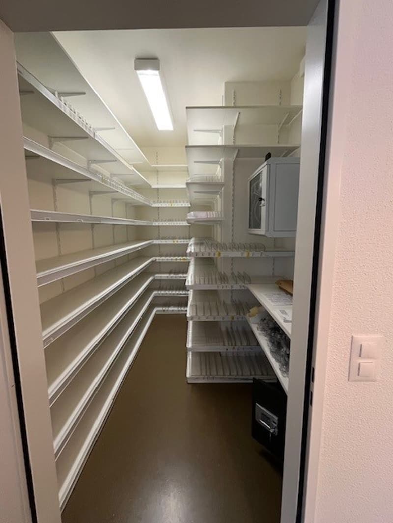 Pantry room, white shelves, microwave oven, white cabinets, brown floor, white walls, bright light