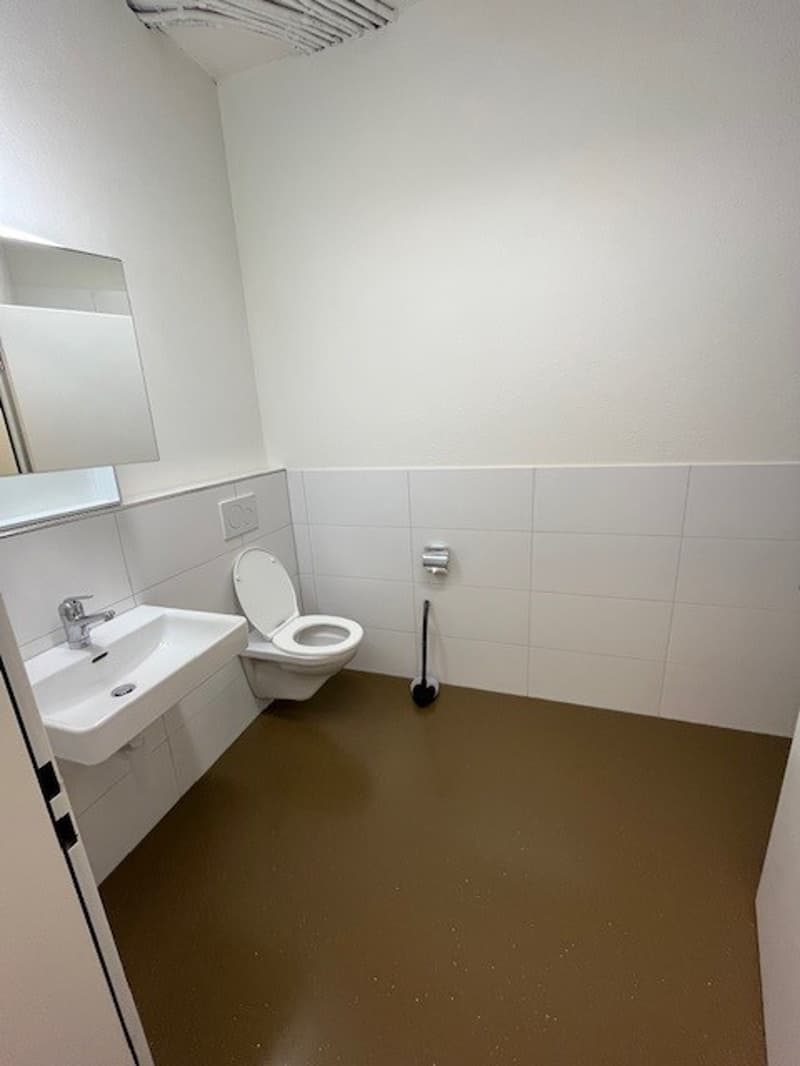 A small bathroom with a toilet, sink, mirror, and floor mounted urinal