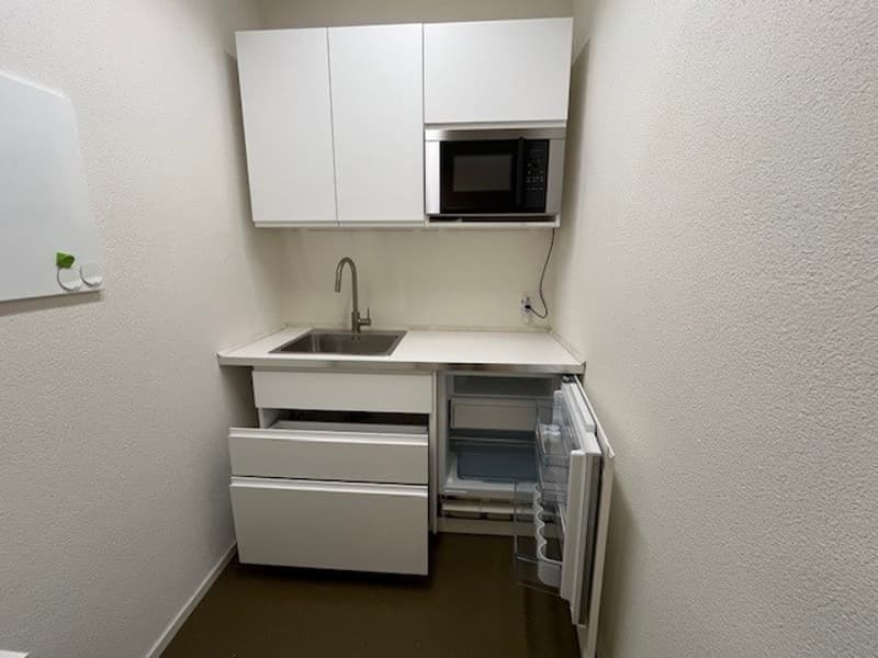 Small kitchen area, with sink, fridge, cabinets, and a microwave
