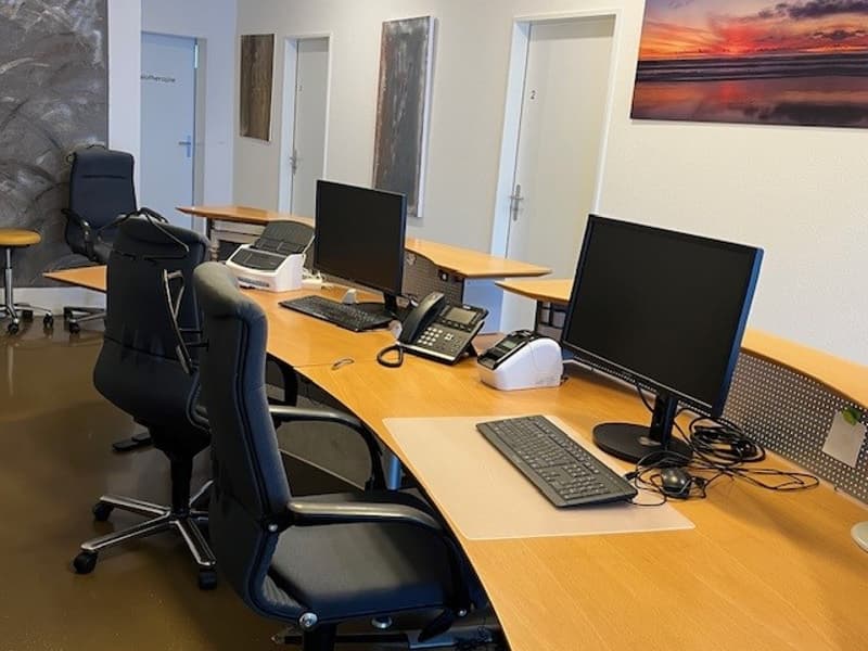 office room with large desk, multiple chairs, computer setups, and phone equipment