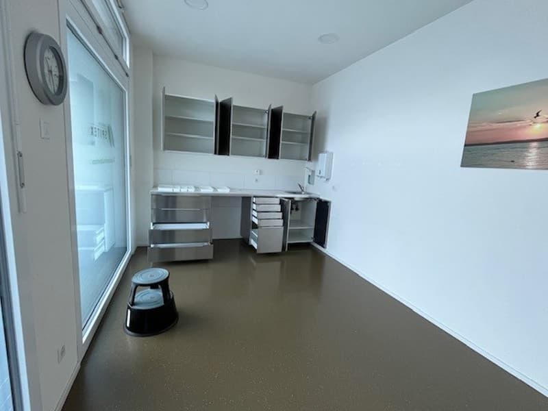 empty room, stainless steel cabinets, white countertops, white walls, clock, open windows, stool