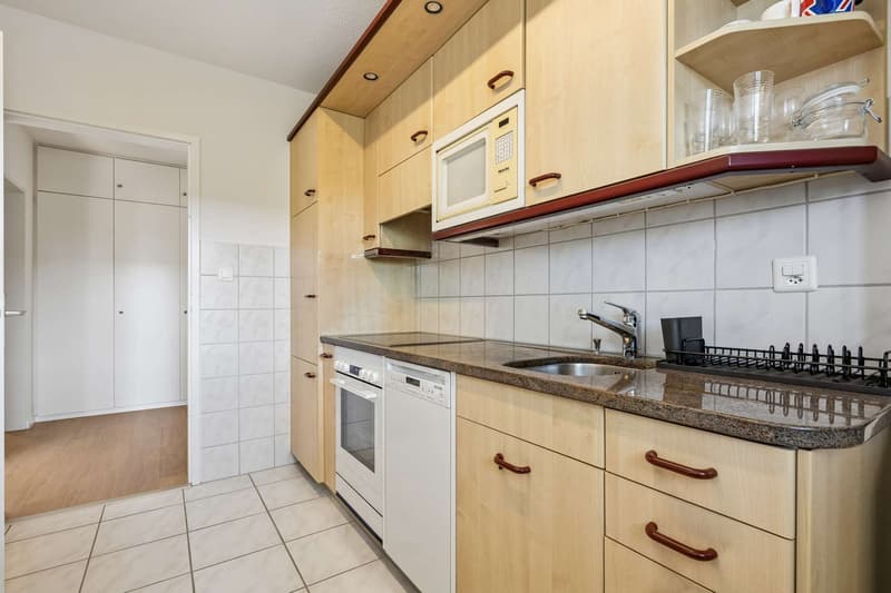 Helle Küche mit Granitabdeckung, Glaskeramik, Kühl- und Gefrierkombination, Geschirrspüler, Mikrowelle und Backofen
