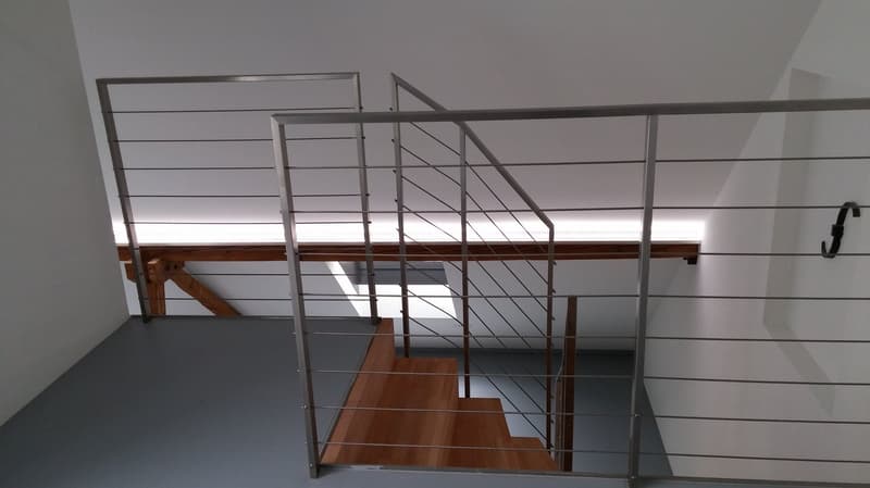 The image shows a staircase with a metal frame and wooden steps. The staircase has a modern, minimalist design with clean lines and a simple, functional appearance.